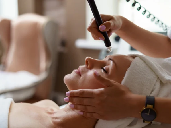 A woman receiving a professional microdermabrasion treatment in a beauty salon.