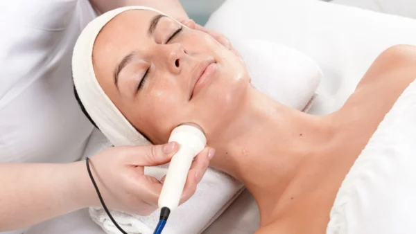 A woman receiving a facial with an ultrasonic cleanser.