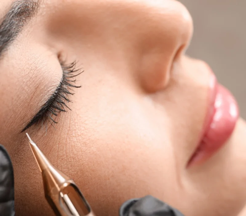 A beauty therapist applying permanent makeup to lips.