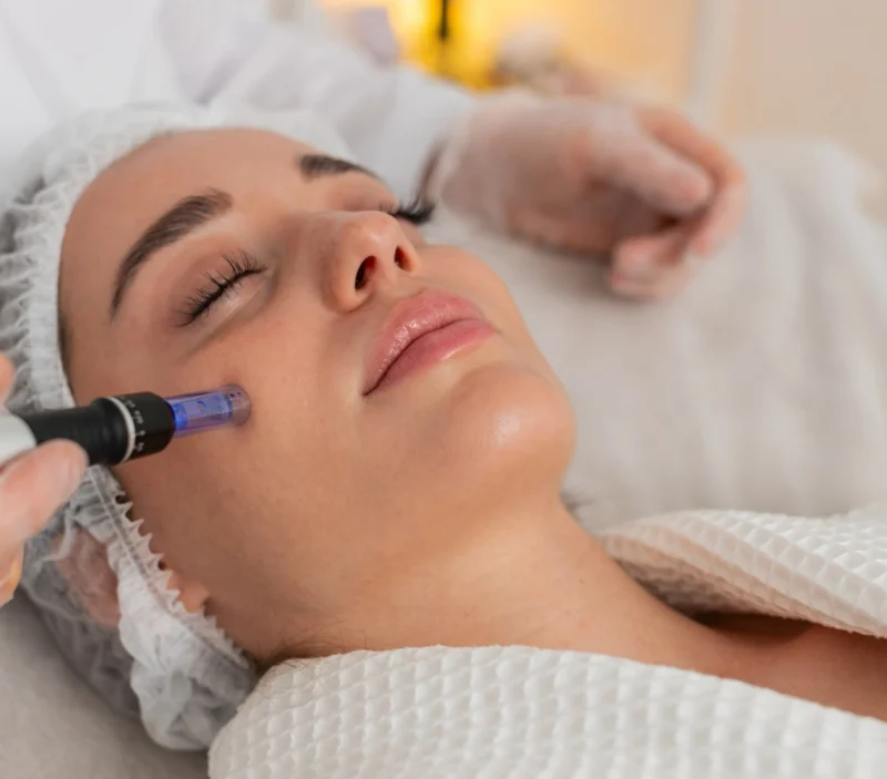 Beauty salon specialist holding mezotix machine to client's face.